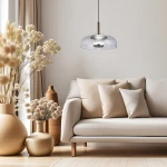 Czarna lampa wisząca Vetro z transparentnym kloszem, zawieszona na cienkim kablu, z jedną diodą LED 6W. Umieszczona nad jasną sofą w nowoczesnym wnętrzu, w otoczeniu dekoracyjnych roślin w donicach.