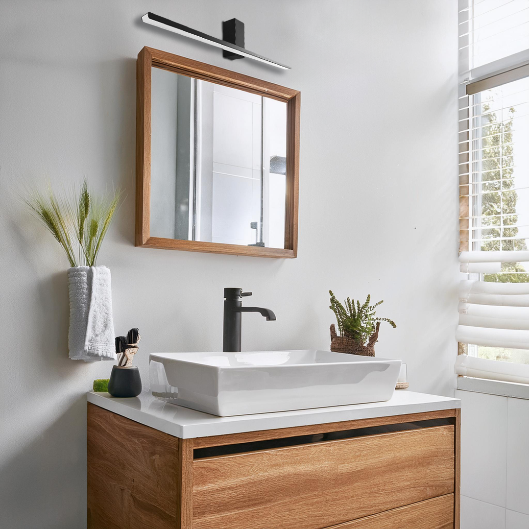 Czarny kinkiet LED Artemis L60, o mocy 13,8W i temperaturze barwowej 4000K, zamontowany nad lustrem w stylowej łazience. Kinkiet ma prostokątny kształt i minimalistyczny design, idealnie komponując się z drewnianą szafką i białą umywalką.