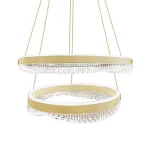 Lampa wisząca Preciosa z dwoma okrągłymi kloszami, złota rama z przezroczystymi kryształkami u dołu, zawieszona na cienkich linkach. Elegancki design, idealna do nowoczesnych wnętrz.