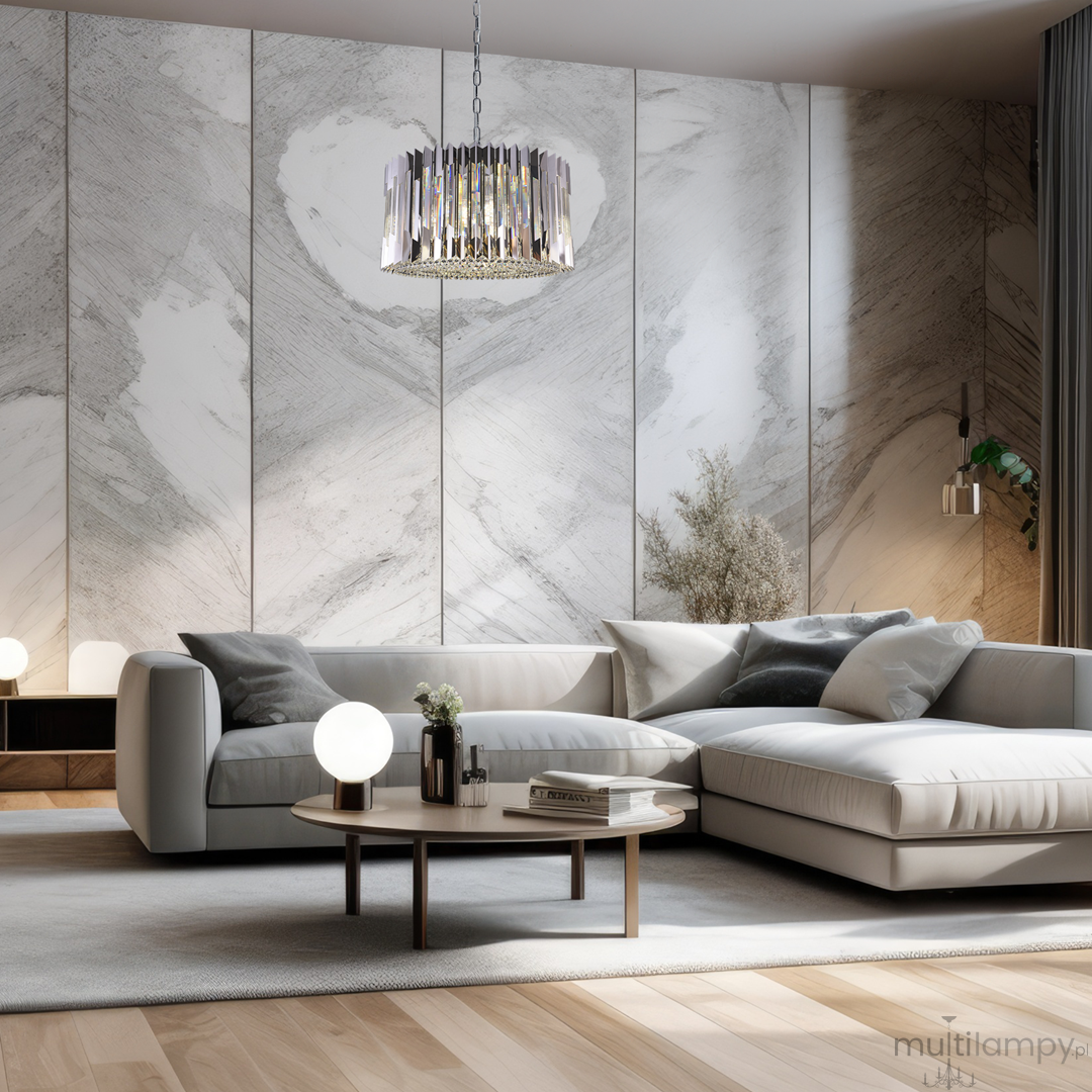 Lampa wisząca Ritz 12xE14 w chromie, z dekoracyjnym abażurem z poziomych, lśniących pasów. Zawieszona na łańcuchu, w nowoczesnym wnętrzu z jasnymi tonami. W tle widoczne elementy aranżacji, w tym szary narożnik i okrągły stół.
