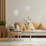 Lampa wisząca Braga 1xE27 w kolorze chromu i białym, o owalnym kształcie z żłobieniami, zawieszona na cienkim kablu. W tle nowoczesny salon z jasną sofą, drewnianymi stolikami i wazonem z białymi kwiatami.