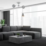 Lampa sufitowa Oakland z chromowanym wykończeniem i dymionymi kloszami, zamontowana na suficie. Posiada dwa źródła światła E27. Otoczenie to nowoczesny salon z szarym narożnikiem, betonowym stolikiem i dużymi oknami.