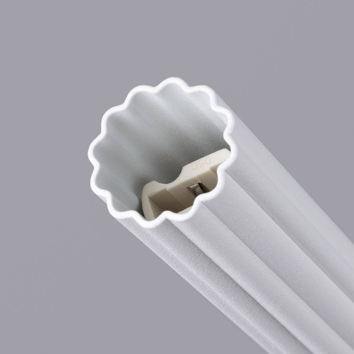 Lampa wisząca Arche 1xG9 w białym kolorze, z falistą krawędzią i teksturowaną powierzchnią. Ujęcie z góry, ukazujące miejsce na żarówkę w kształcie prostokąta. Tło w stonowanym odcieniu szarości, podkreślające detale lampy.