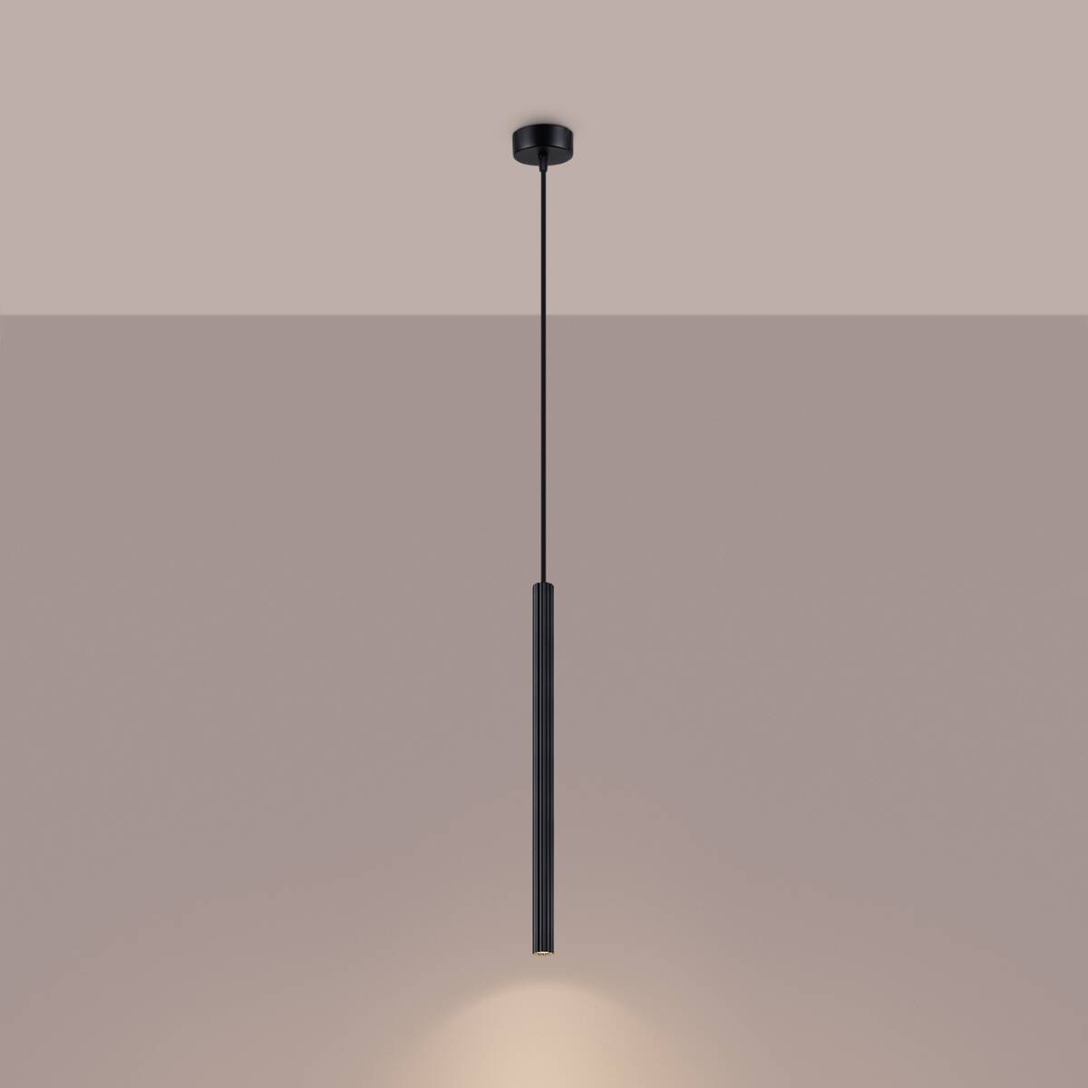 Lampa wisząca Arche w kolorze czarnym, z pojedynczym źródłem światła G9. Ma prostą, cylindryczną formę z teksturowaną powierzchnią. Zawieszona na cienkim, czarnym przewodzie, emitując światło w dół. Tło w odcieniu jasnego beżu.