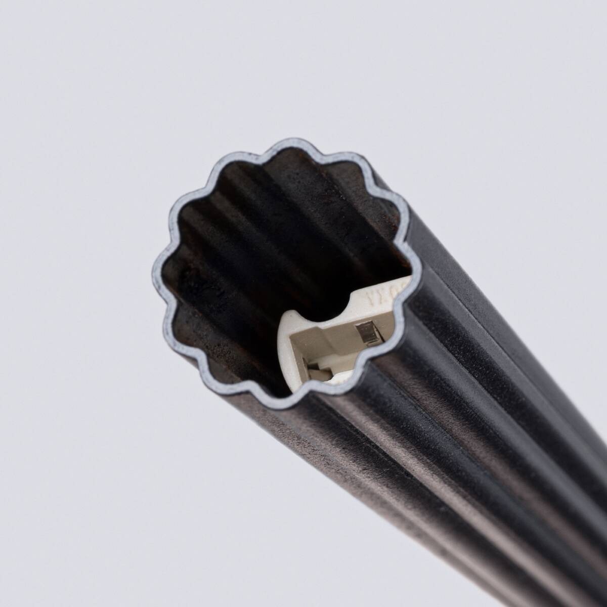 Lampa wisząca Arche w kolorze czarnym, z gniazdem na żarówkę G9. Fragment lampy widoczny z bliska, ukazujący falisty kształt oraz wnętrze ze złączem elektrycznym. Tło jasne, co podkreśla detale produktu.