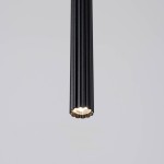 Lampa wisząca Arche w kolorze czarnym, z metalowym, podłużnym kloszem w kształcie rurki z żłobieniami. Widoczna oprawa na żarówkę G9, umieszczona na końcu klosza. Produkt zawieszony w pionie na jasnym tle.
