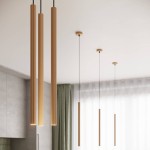 Lampa wisząca Arche 1xG9 w kolorze złotym, składająca się z czterech podłużnych, teksturowanych elementów. Zawieszona na cienkich linkach, umieszczona w nowoczesnym wnętrzu z jasnym tłem i zasłonami.