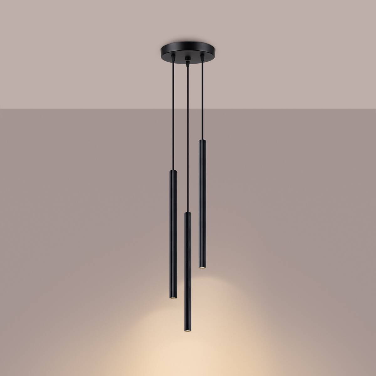 Lampa wisząca Arche w kolorze czarnym z trzema cylindrycznymi abażurami G9, zawieszona na cienkich linkach. Ujęcie z góry, z widocznym źródłem światła, które oświetla przestrzeń poniżej. Prosty, nowoczesny design.
