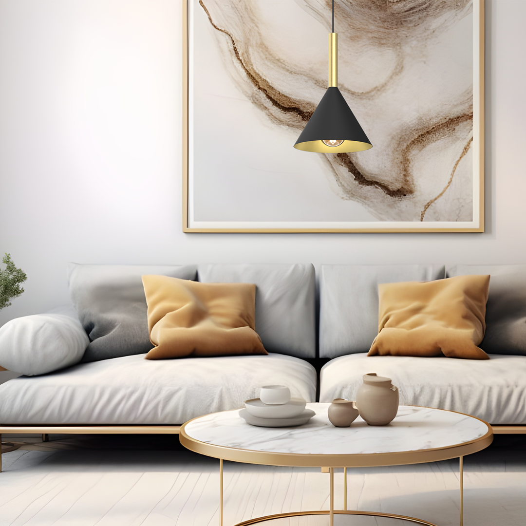 Lampa wisząca Peru w kolorze czarnym i złotym z kloszem w kształcie stożka, zawieszona nad białym stołem kawowym. W tle nowoczesny obraz z abstrakcyjnymi wzorami. Sofy w odcieniach szarości z poduszkami w kolorze złotym.