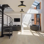 Czarna lampa sufitowa Felix z metalowym kloszem i złotym wnętrzem, zamontowana na suficie w nowoczesnym wnętrzu. Widoczna w aranżacji z spiralnymi schodami i kanapami, oświetla przestrzeń dzienną.