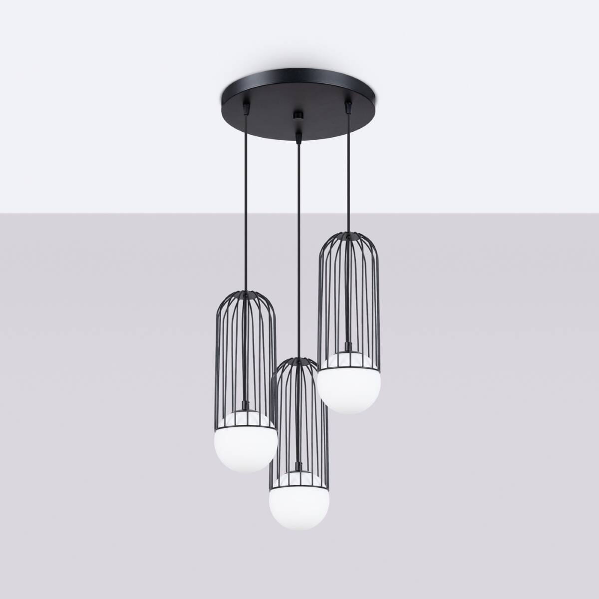 Lampa wisząca Brina 3P z trzema kloszami w formie metalowych klatek, w kolorze czarnym. Klosze mają białe, okrągłe odbłyśniki. Ujęcie z dołu, lampa zawieszona na cienkich przewodach, przymocowana do okrągłej, czarnej podstawy sufitowej.