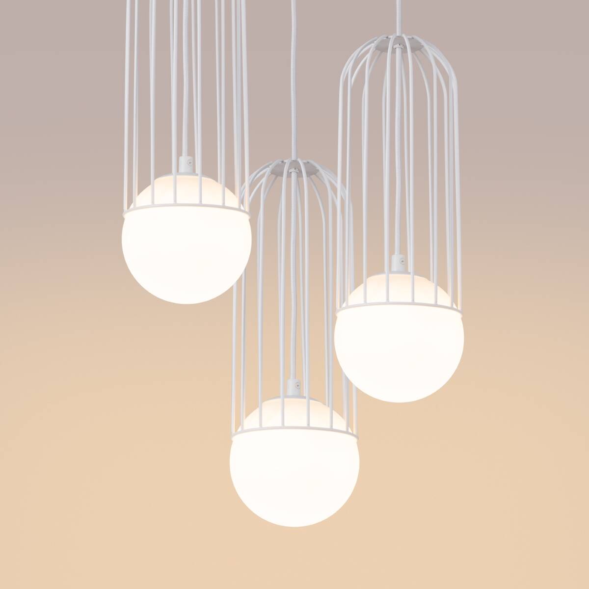 Lampa wisząca Brina 3P w białej kolorystyce, z trzema okrągłymi kloszami z matowego szkła, umieszczonymi w metalowej, białej klatce. Produkt zawieszony na białych przewodach, na jednolitym tle.