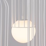 Lampa wisząca Brina 3P w kolorze białym z trzema źródłami światła G9. Widoczna okrągła, matowa kula w metalowej, białej klatce. Ujęcie z bliska, koncentrujące się na detalu lampy i jej struktury.