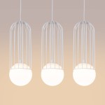 Lampa wisząca Brina 3xG9 w białym kolorze, z trzema okrągłymi kloszami w mlecznym odcieniu, osłoniętymi metalową, białą siatką. Zawieszona na białych kablach, w minimalistycznym stylu, na jednolitym tle.