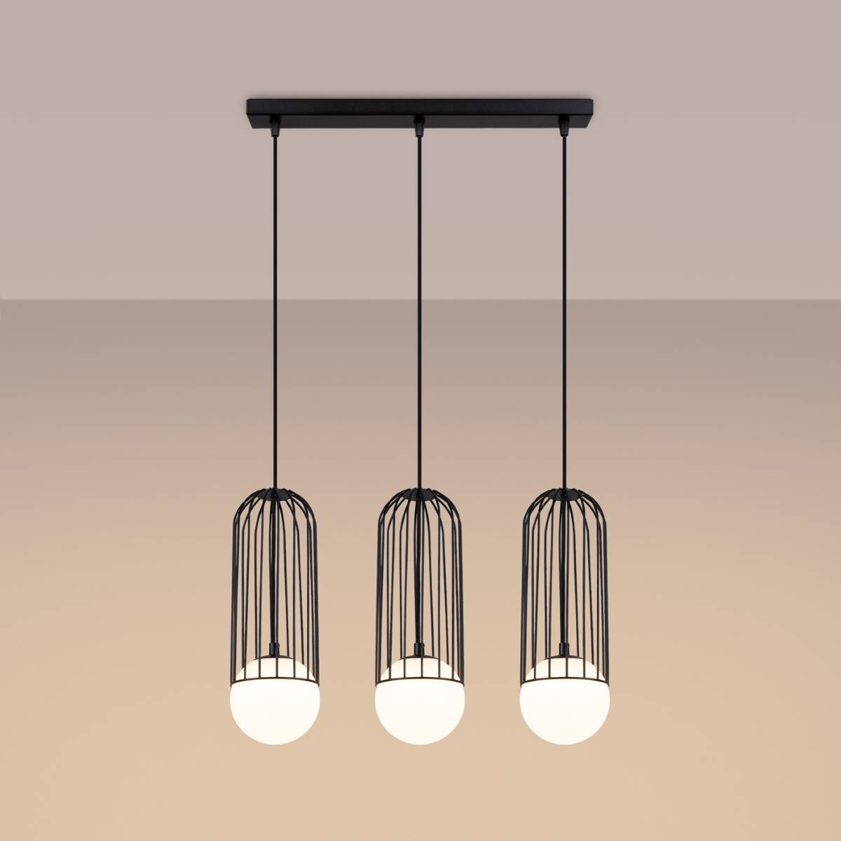 Lampa wisząca Brina z trzema kloszami G9 w czarnych metalowych osłonach w kształcie cylindrów. Klosze z białymi kulistymi żarówkami zawieszone na cienkich linkach. Ujęcie frontalne na jednolitym tle.