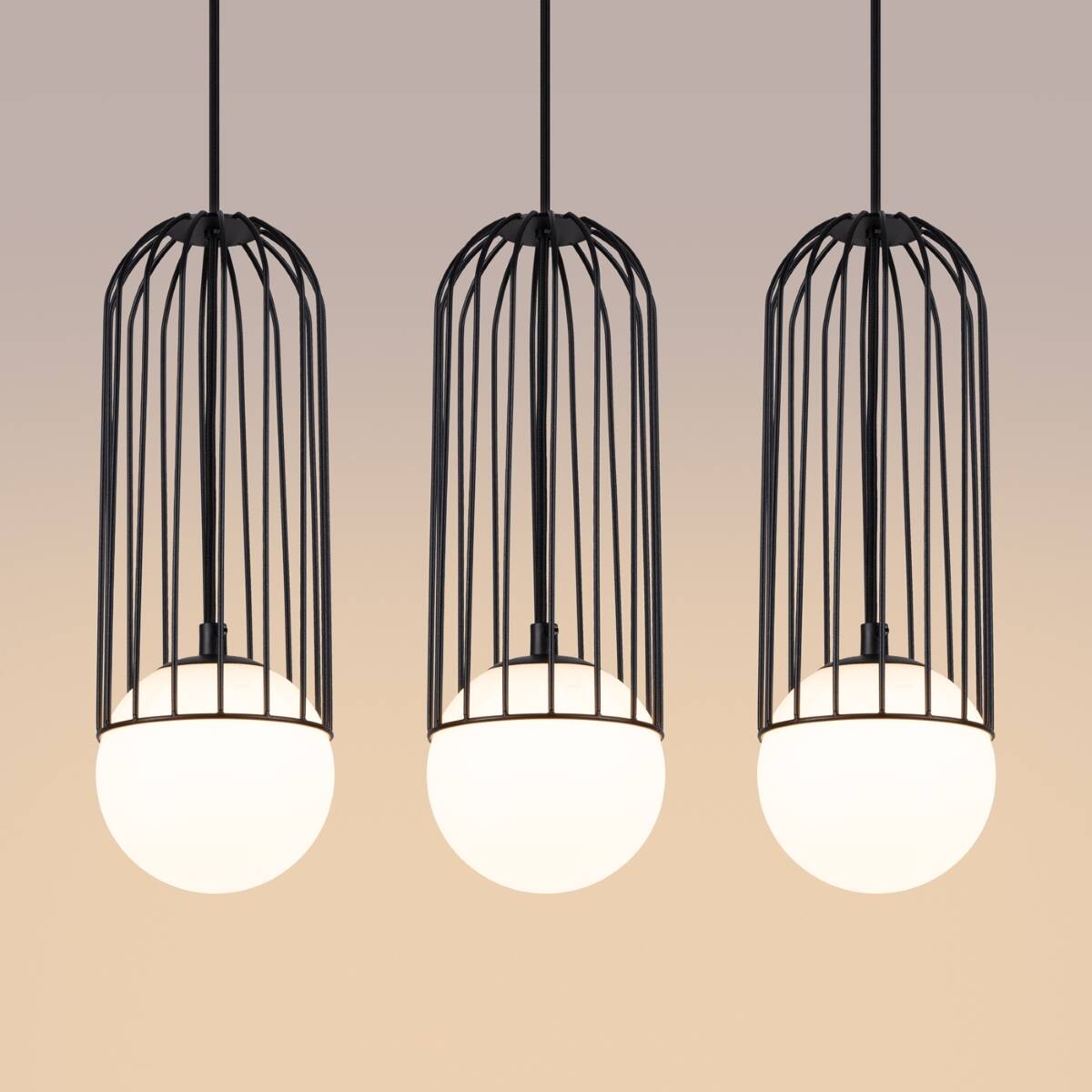 Czarna lampa wisząca Brina z trzema kloszami w formie kulek, umieszczona w metalowych klatkach, z mocowaniem do sufitu. Klosze mają matową, białą powierzchnię, a całość zawieszona na cienkich linkach. Tło w stonowanym odcieniu.