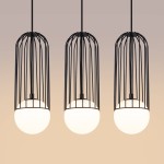 Czarna lampa wisząca Brina z trzema kloszami w formie kulek, umieszczona w metalowych klatkach, z mocowaniem do sufitu. Klosze mają matową, białą powierzchnię, a całość zawieszona na cienkich linkach. Tło w stonowanym odcieniu.