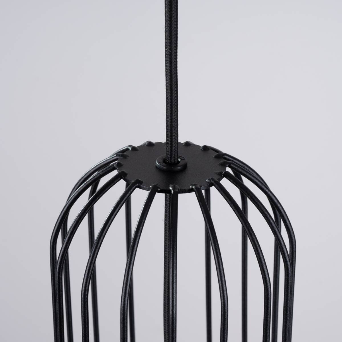 Czarna lampa wisząca Brina z jednym gniazdem G9, widok z góry na metalową konstrukcję z otwartym kloszem, zbudowaną z cienkich prętów w kształcie klatki. Uchwyt w formie okrągłej podstawy z elementem mocującym. Tło jasne, proste.