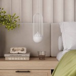 Lampa wisząca Brina 1xG9 w kolorze białym, z metalową klatką i okrągłym kloszem. Zawieszona nad drewnianą szafką nocną, obok książek i szklanki. Tło w neutralnych odcieniach, z teksturą ściany i poduszki.