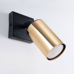 Kinkiet Winx w kolorze czarnym i złotym, z metalowym kloszem w formie walca. Uchwyt zamocowany do ściany, z widocznym źródłem światła GU10. Klosz skierowany w dół, na prostym, jasnym tle.