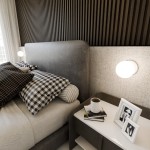 Białe kinkiet 1-punktowy Bior 1021/K1 zamontowany na ścianie obok łóżka. Na tle znajduje się szary zagłówek oraz poduszki w czarno-białe wzory. Obok kinkietu stół nocny z książkami i filiżanką. Tło jest neutralne, z teksturą.