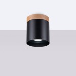Lampa sufitowa Rif tuba w kolorze czarnym z drewnianym wykończeniem. Montowana na suficie, z cylindrycznym kształtem, posiada miejsce na żarówkę GU10. Widoczna biała oprawa wewnętrzna. Tło jasne, proste.