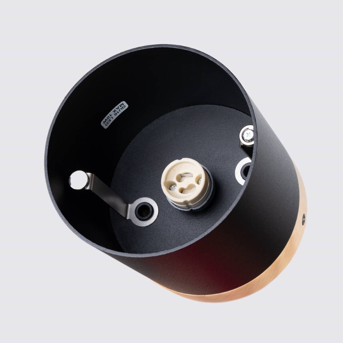 Czarna lampa sufitowa tuba z drewnianym wykończeniem, widok od góry. Zawiera gniazdo GU10 oraz metalowe mocowania. Prosty design, idealna do nowoczesnych wnętrz. Tło jasnoszare, podkreślające detale lampy.