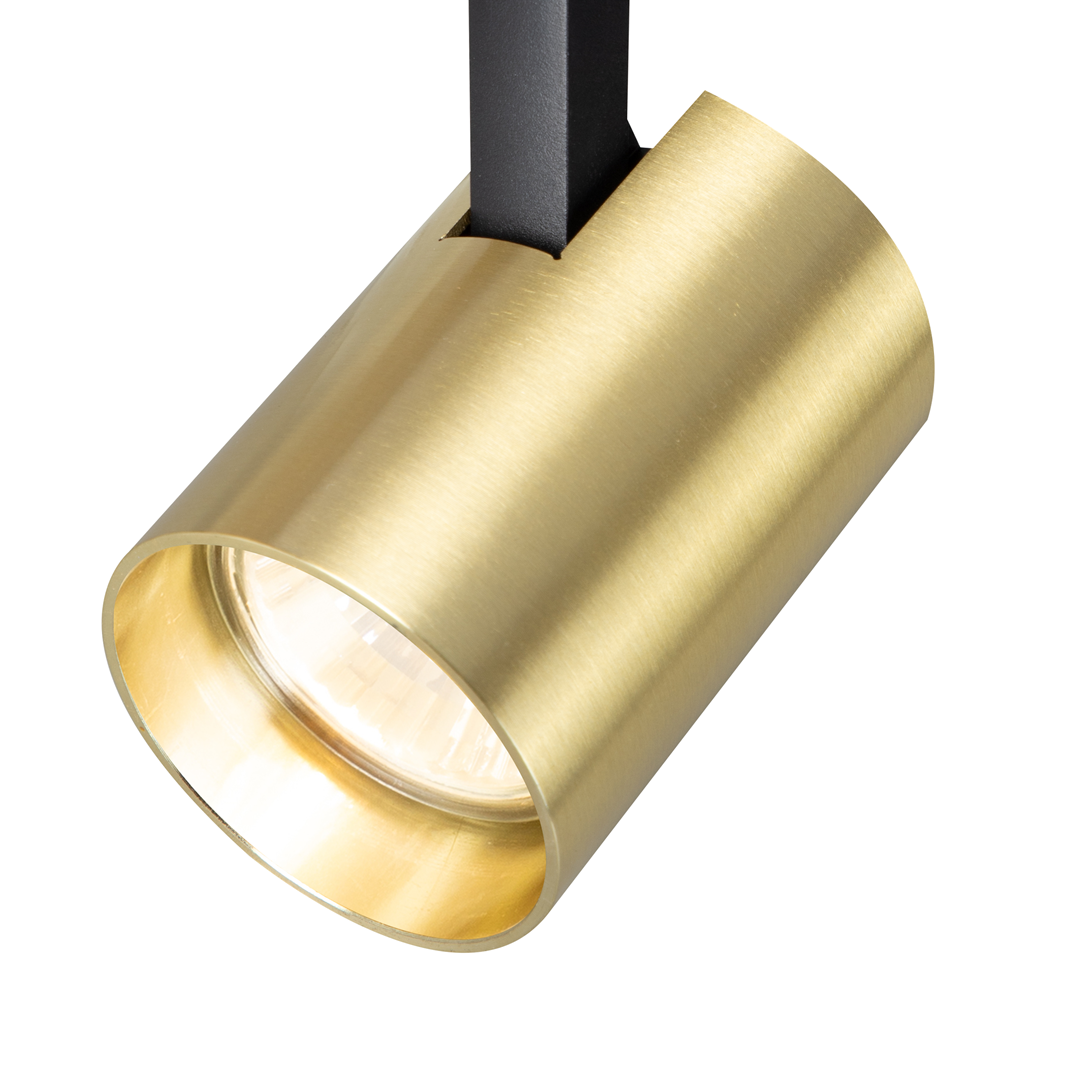 Reflektor spot Track Volf w kolorze czarnym i złotym, z metalowym, cylindrycznym kloszem w odcieniu złota. Ujęcie z bliska, pokazujące detal lampy z widocznym źródłem światła GU10. Element zamocowany na czarnym uchwycie.