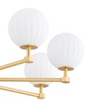 Żyrandol Paloma w kolorze mosiądzu z białymi kulistymi kloszami. Posiada cztery ramiona z kwadratowymi mocowaniami, które podtrzymują lampy. Klosze mają teksturowaną powierzchnię, co dodaje elegancji. Idealny do nowoczesnych wnętrz.