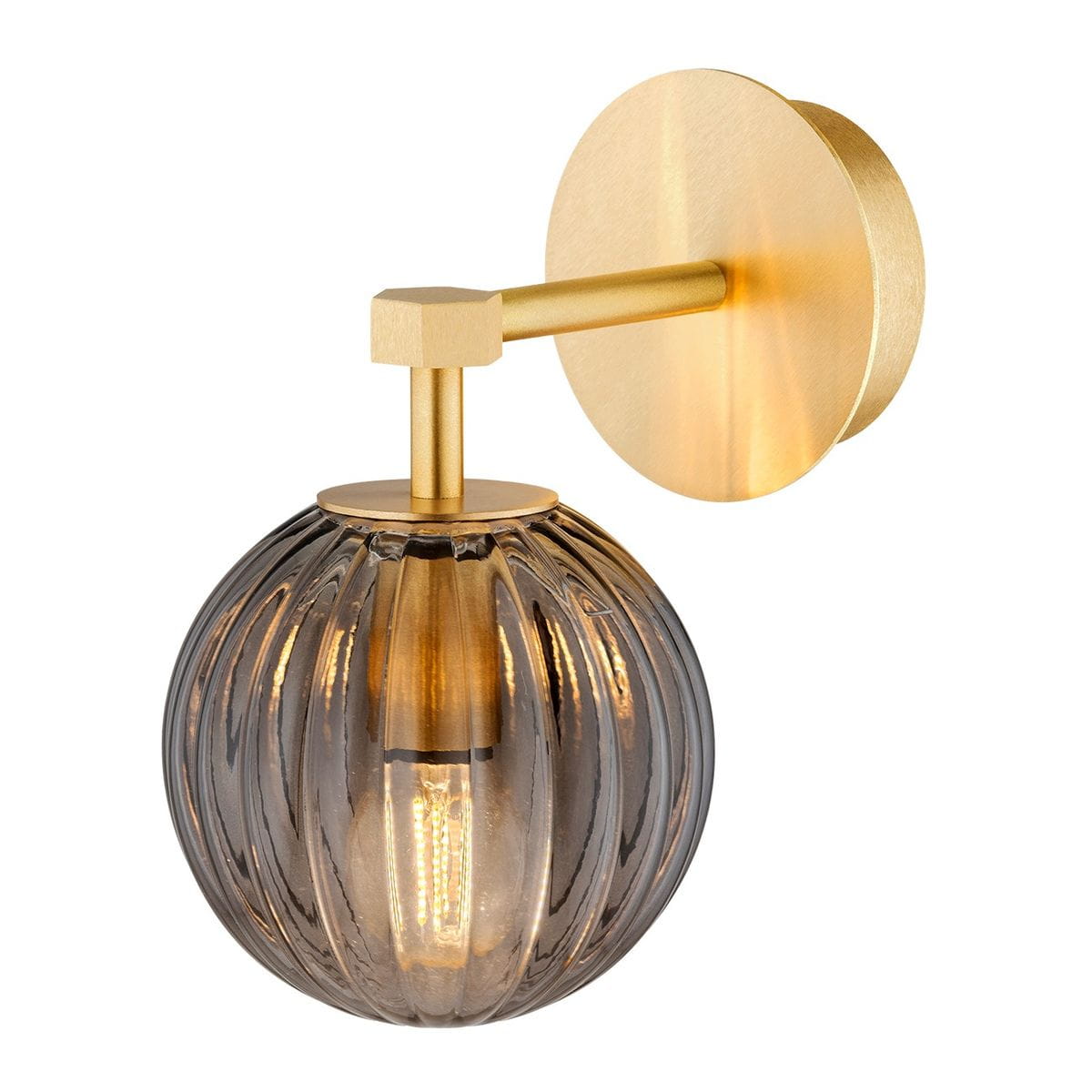 Kinkiet Paloma w kolorze mosiądzu z dymną, szklaną kulą. Okrągła, złota podstawa oraz prostokątny uchwyt. Widoczna żarówka E14 w przezroczystej obudowie, z delikatnym żłobieniem na szkle. Produkt zamontowany na ścianie, w ujęciu z boku.
