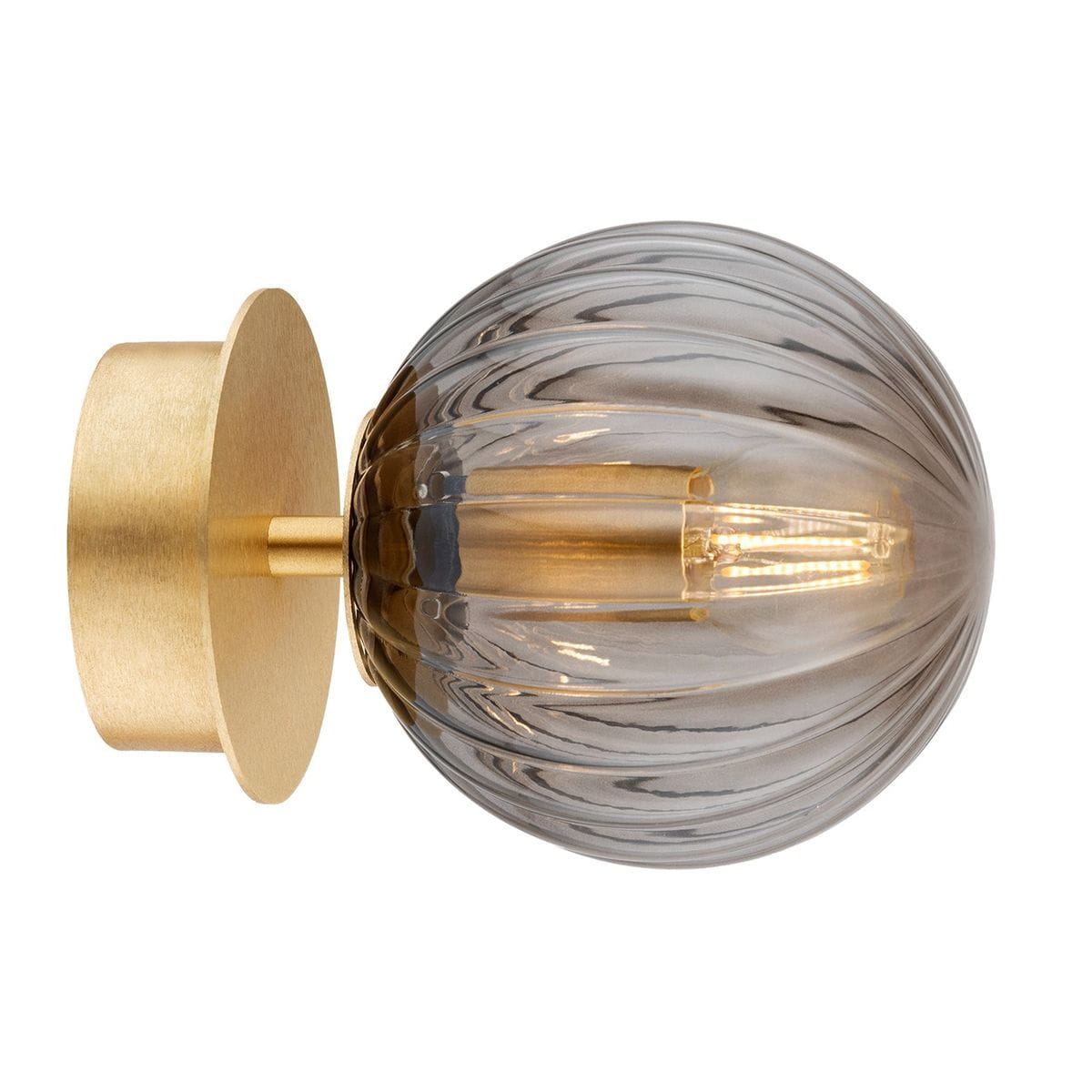 Kinkiet Paloma 1xE14 w kolorze mosiądzu z dymnym kloszem. Okrągły, szklany klosz z pionowymi żłobieniami, zamontowany na okrągłej, matowej podstawie. Produkt widoczny z boku, podkreślający elegancki design.