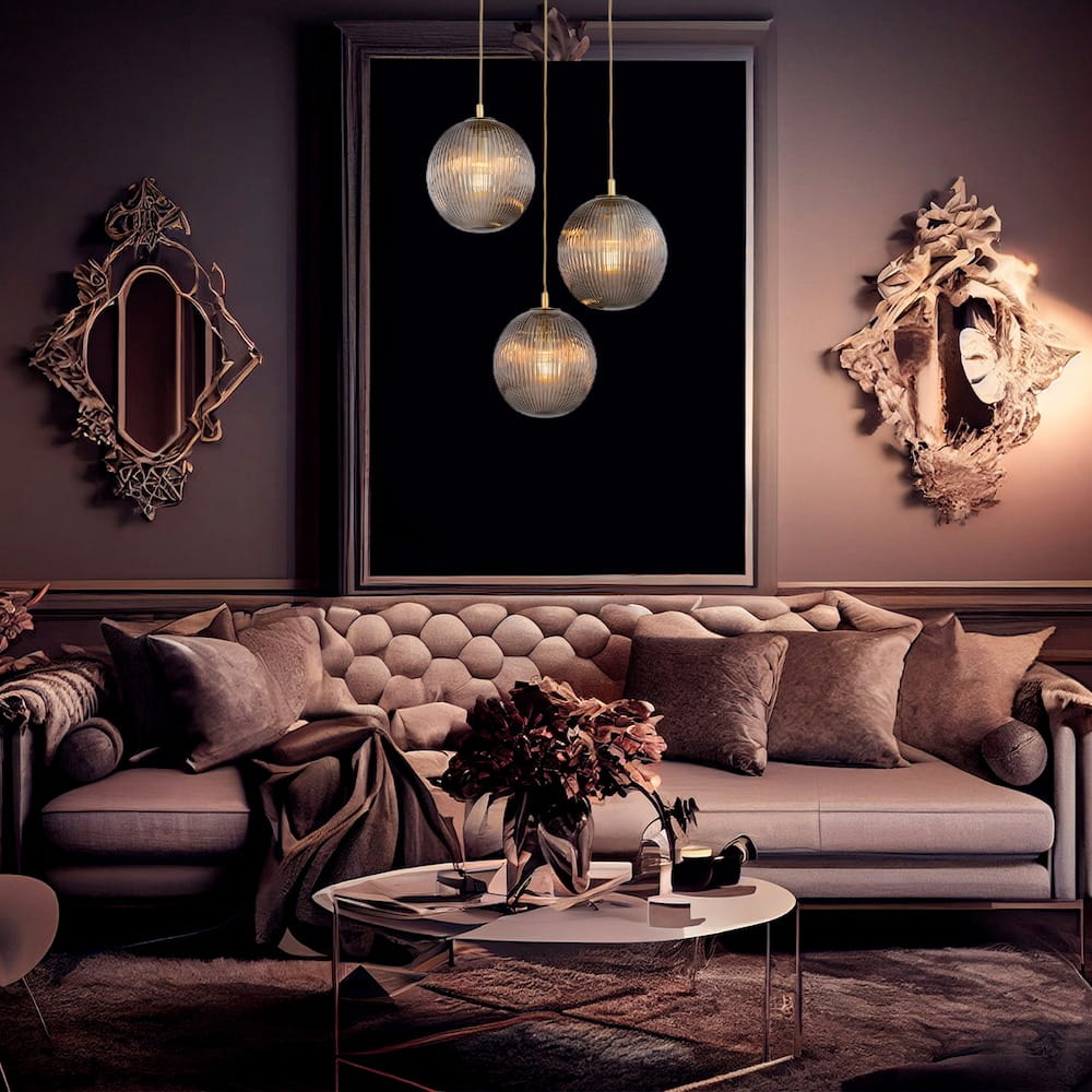 Lampa wisząca Paloma z trzema kloszami E27 w dymnym szkle, zawieszona na złotych linkach. Klosze mają żłobioną fakturę, tworząc efektowne światło. Lampa umieszczona w eleganckim wnętrzu z szaro-beżową kanapą i ozdobnym lustrem w tle.