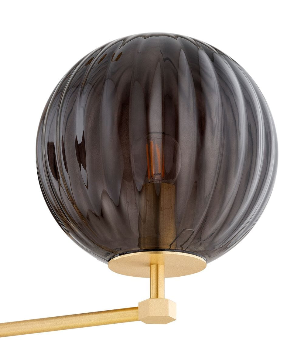 Żyrandol Paloma 3xE14 w mosiężnym wykończeniu z dymnym, szklanym kloszem w kształcie kuli. Klosz ma falistą fakturę, a metalowa podstawa jest w kolorze złotym. Produkt zawieszony na prostym ramieniu, idealny do nowoczesnych wnętrz.