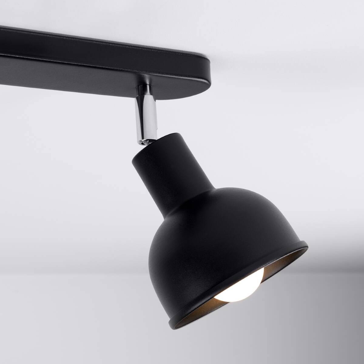Czarna lampa sufitowa Elba z dwoma spotami E27, umieszczona pod kątem. Metalowy klosz o okrągłym kształcie z matowym wykończeniem, z widoczną żarówką. Elementy montażowe w kolorze chromu, zamocowane do prostokątnej podstawy.