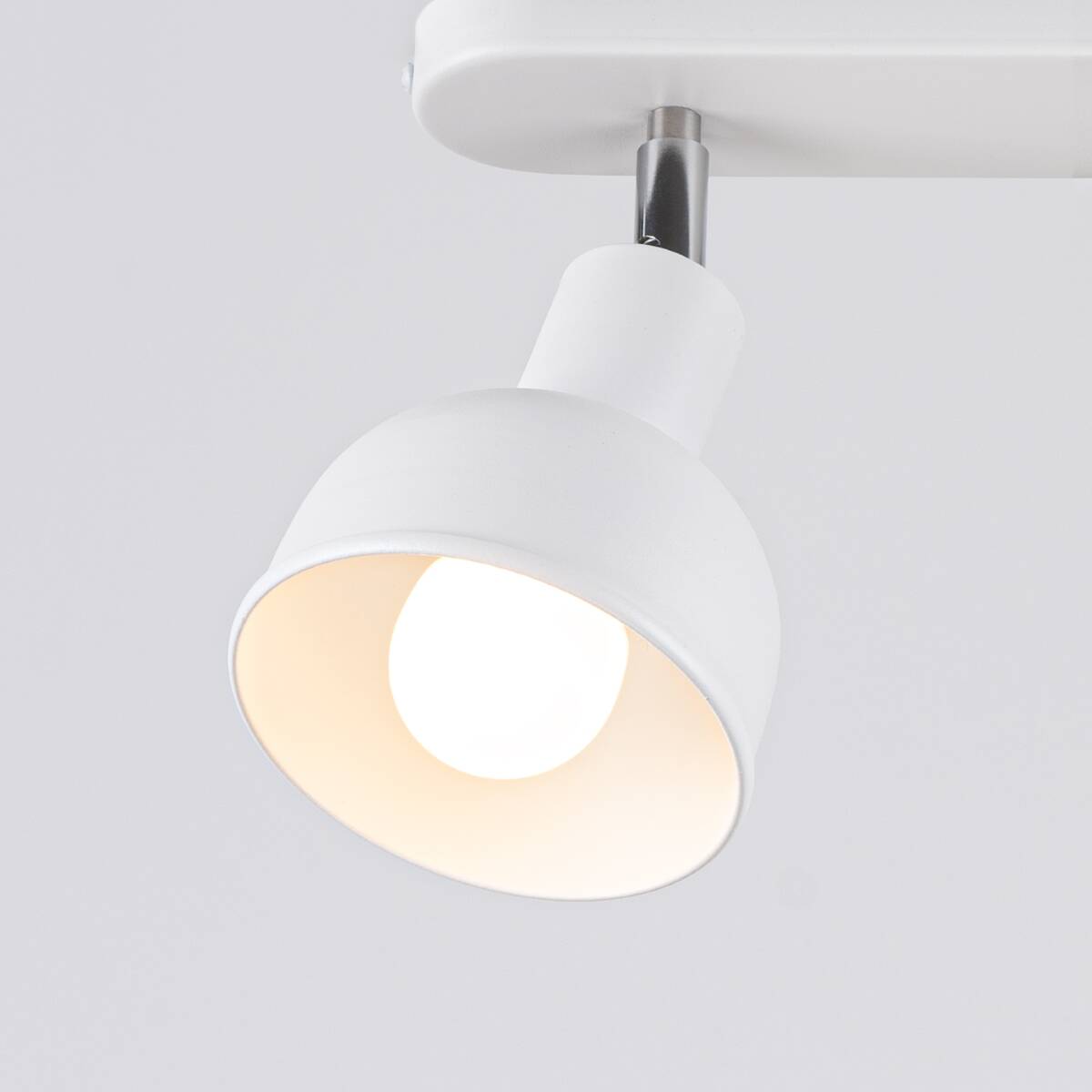 Lampa sufitowa Elba w kolorze białym z dwoma oprawami E27. Ujęcie z bliska, pokazujące okrągły klosz, który jest matowy z wnętrzem białym. Metalowy uchwyt łączy klosz z podwieszeniem, na gładkim jasnym tle.