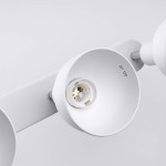 Lampa sufitowa Elba w kolorze białym z trzema oprawami na żarówki E27. Zbliżenie na jedną z opraw, ukazującą gwint oraz oznaczenia maksymalnej mocy. Ułożona poziomo, na tle jasnej powierzchni.