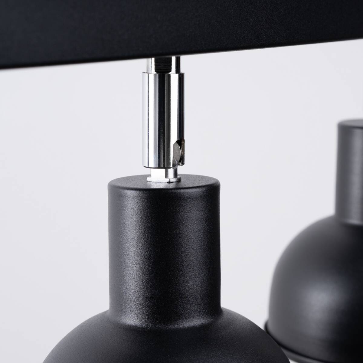 Lampa sufitowa Elba, z trzema miejscami na żarówki E27, w kolorze matowej czerni. Widok z bliska pokazuje metalowe mocowanie oraz podstawę lampy, z chromowanym detalem łączącym elementy. Tło jasne, podkreślające design.
