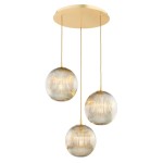 Lampa wisząca Paloma z trzema żarówkami E27, w kolorze mosiądzu i szarym, z okrągłymi szklanymi kloszami o żłobionej fakturze. Produkt zawieszony na złotym stropie, z długimi linkami, w układzie symetrycznym.