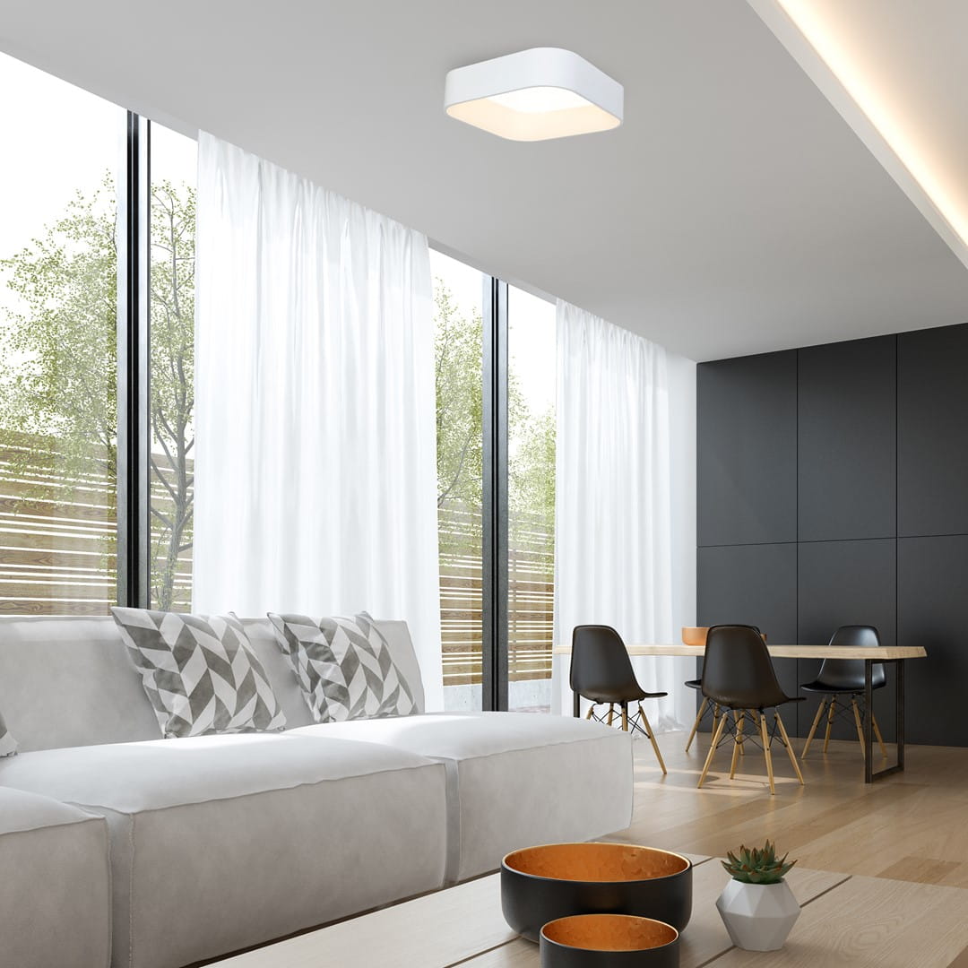 Lampa sufitowa LED Astro ML6355 o mocy 40W w białej obudowie, zamontowana na suficie w nowoczesnym wnętrzu. W tle widoczne okna z białymi zasłonami, kanapa z poduszkami oraz stół z krzesłami.