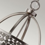 Lampa wisząca Zara 4xE14 w satynowym niklu, z metalową konstrukcją. Górna część w formie elipsy z dekoracyjnymi elementami, zawieszona na przezroczystym kablu. Widać okrągły uchwyt mocujący. Tło w odcieniach szarości.
