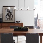 Lampa wisząca Rubin w satynie niklowej z 10 źródłami światła G9, zamontowana nad drewnianym stołem. Szklane klosze o geometrycznym kształcie, w otoczeniu minimalistycznych mebli i dekoracji, tworzą nowoczesne wnętrze.