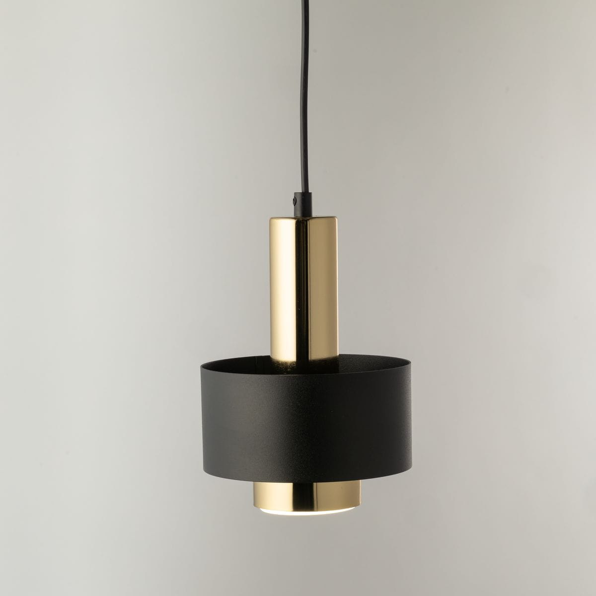 Lampa wisząca Rif Lux D15 z jedną żarówką GX53, w kolorze czarnym i złotym. Posiada cylindryczny kształt z matowego czarnego metalu i błyszczącego złotego detalu u góry. Zawieszona na czarnym przewodzie, prezentuje minimalistyczny design.