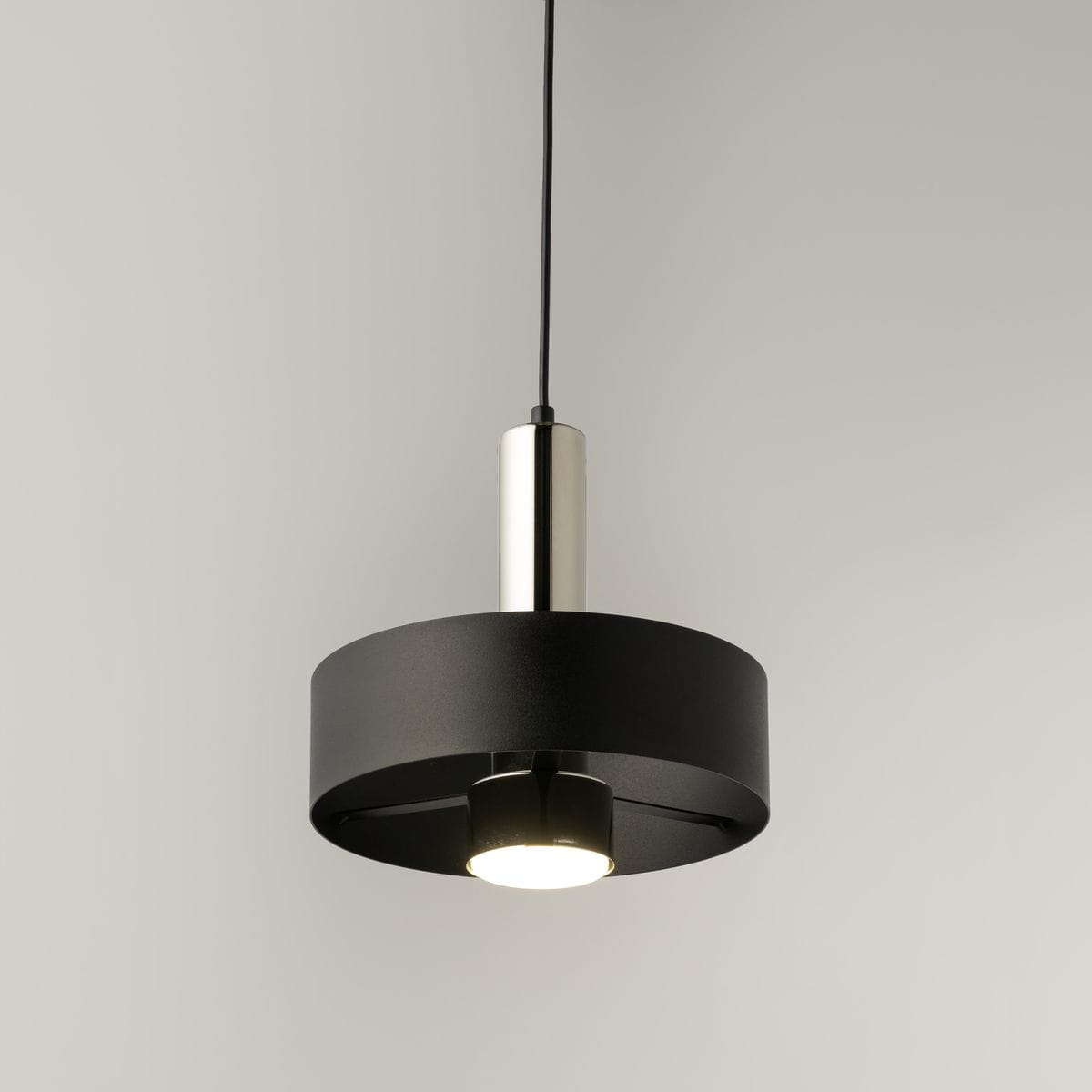 Lampa wisząca Rif Lux D25 w kolorze czarnym z metalowym, srebrnym wykończeniem. Okrągła konstrukcja z widocznym źródłem światła GX53, zawieszona na cienkim przewodzie. Prosty, nowoczesny design, idealna do wnętrz.