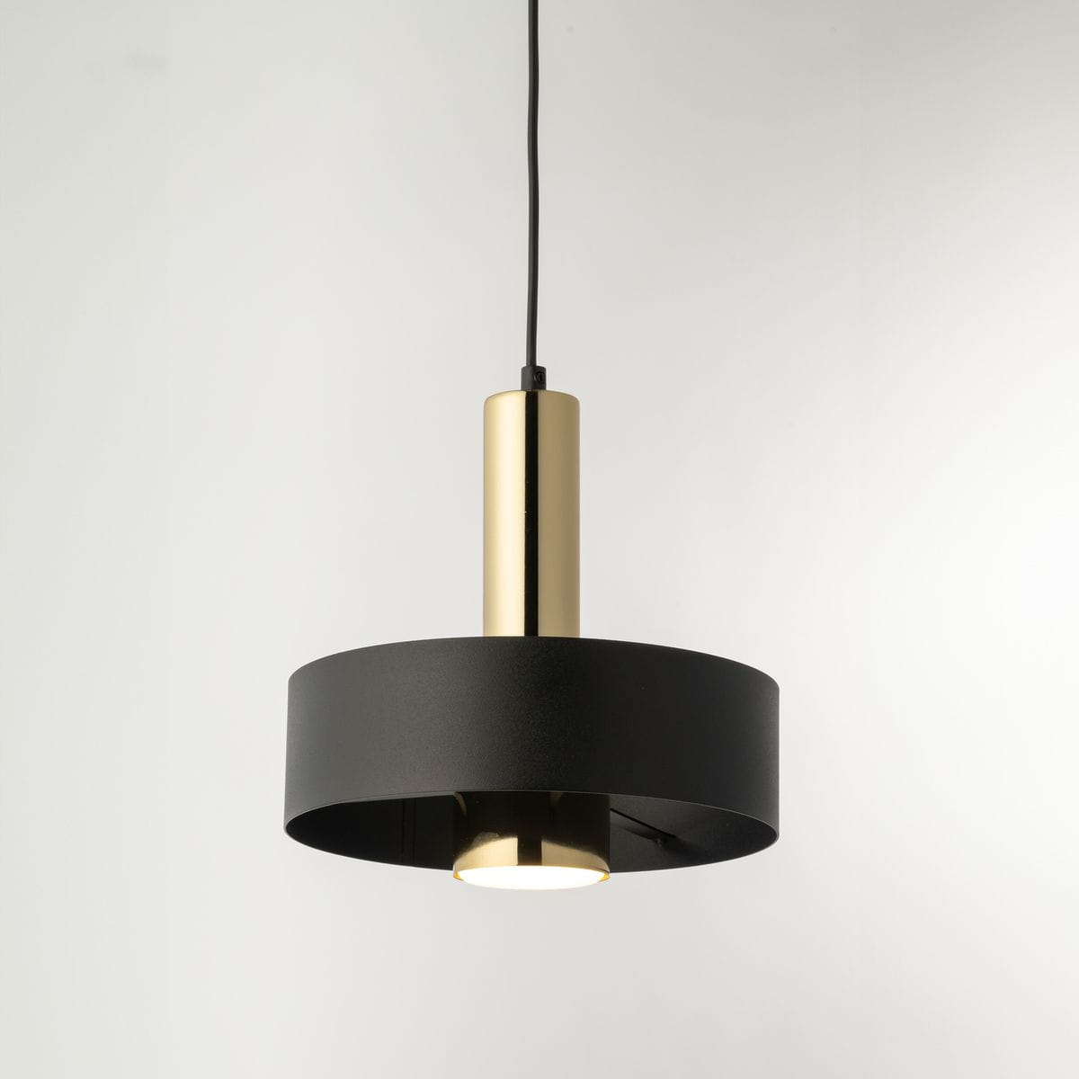 Lampa wisząca Rif Lux D25 z czarnym metalowym kloszem i złotym wykończeniem. Ujęcie z boku, zawieszona na czarnym przewodzie. Źródło światła GX53 w centralnej części klosza. Prosty, nowoczesny design.