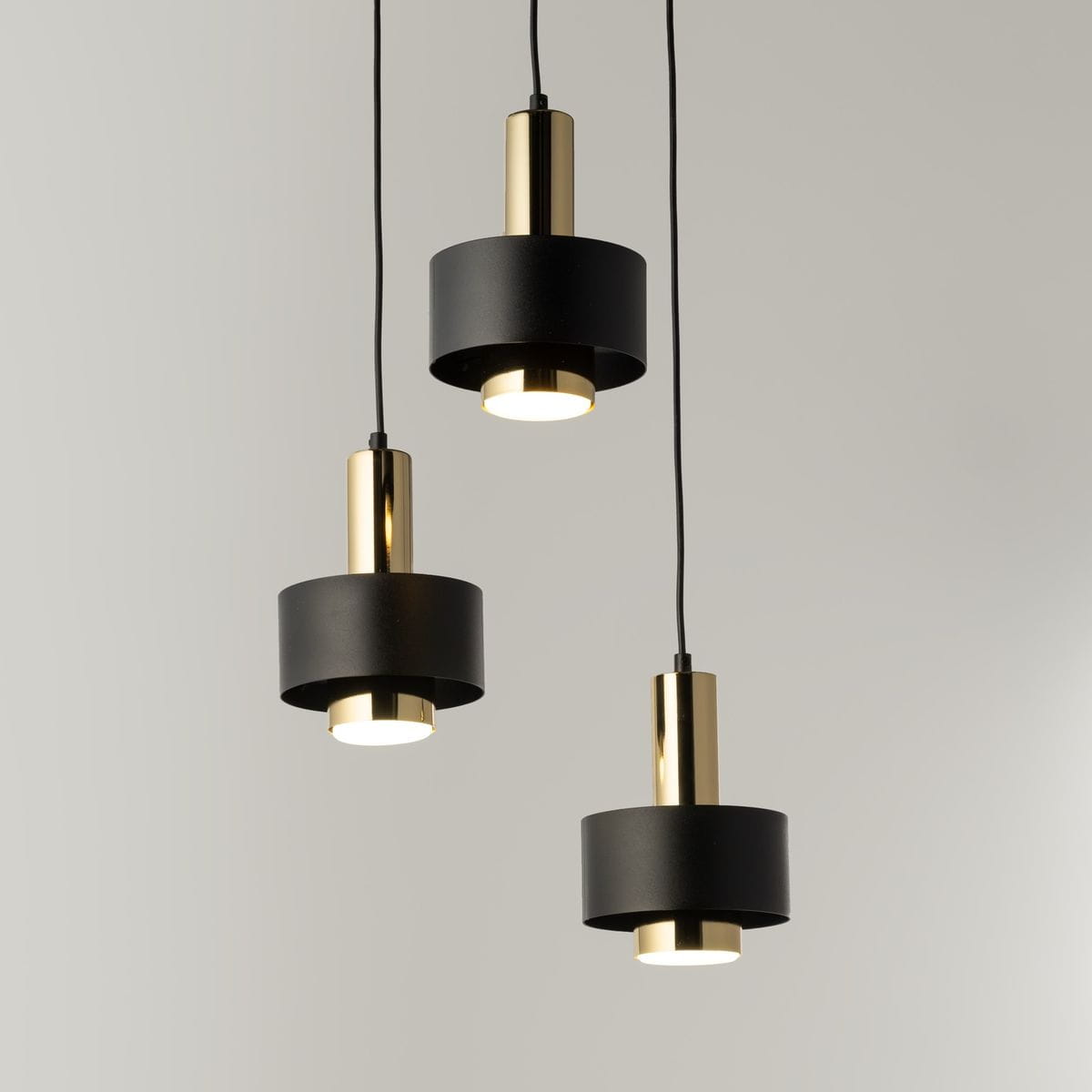 Lampa wisząca Rif Lux z trzema źródłami światła GX53 w kolorze czarnym i złotym. Składa się z cylindrycznych kloszy z matowym wykończeniem oraz metalowych, błyszczących elementów. Zawieszona na cienkich przewodach, w różnej wysokości.