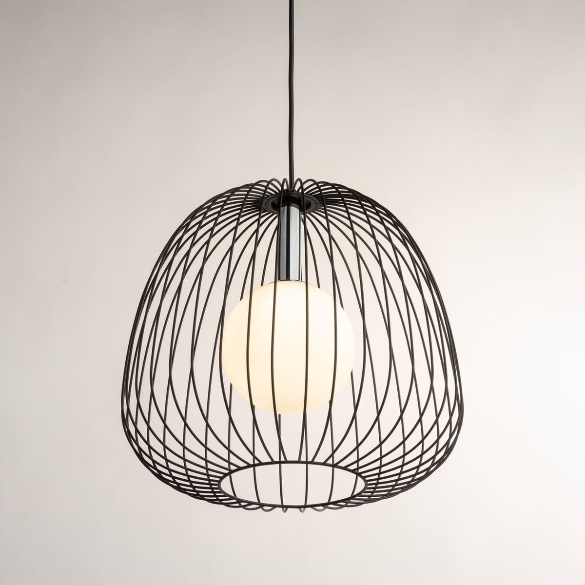 Lampa wisząca Bell D33 w kolorze czarnym i srebrnym z metalową, siatkowatą obudową. Wewnątrz znajduje się okrągła, biała żarówka G9. Ujęcie z góry, prezentujące detal konstrukcji oraz kształt lampy.