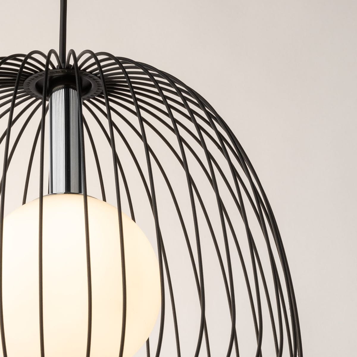 Czarna lampa wisząca Bell D33 z metalową siatką, z okrągłym, białym kloszem. Widok z góry, ukazujący detale konstrukcji oraz chromowane mocowanie. Lampa przeznaczona do jednego źródła światła G9. Tło w jasnym odcieniu.