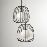 Lampa wisząca Bell z dwiema oprawami G9, w czarnej metalowej klatce z okrągłymi białymi kloszami. Ujęcie z przodu, dwa klosze umieszczone jeden pod drugim, na jasnym tle. Elementy dekoracyjne w minimalistycznym stylu.