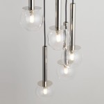 Lampa wisząca Daisy z pięcioma kulistymi kloszami w kolorze transparentnym na srebrnych elementach. Kształt cylindrów i kul nadaje nowoczesny wygląd. Produkt zawiera źródła światła G9 i zawieszony jest na czarnych przewodach.