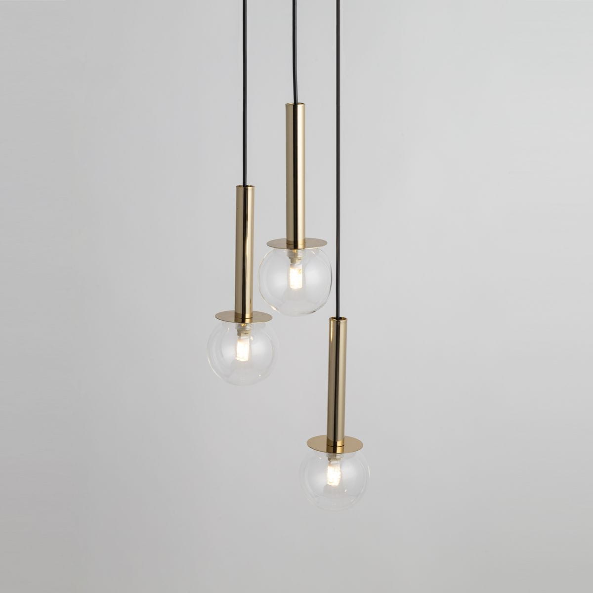Lampa wisząca Daisy 3xG9, złote metalowe podstawy z przezroczystymi kloszami w kształcie kul, zawieszone na czarnych kablach. Klosze mają okrągłe podstawy, a całość jest zawieszona na tle jasnej ściany.